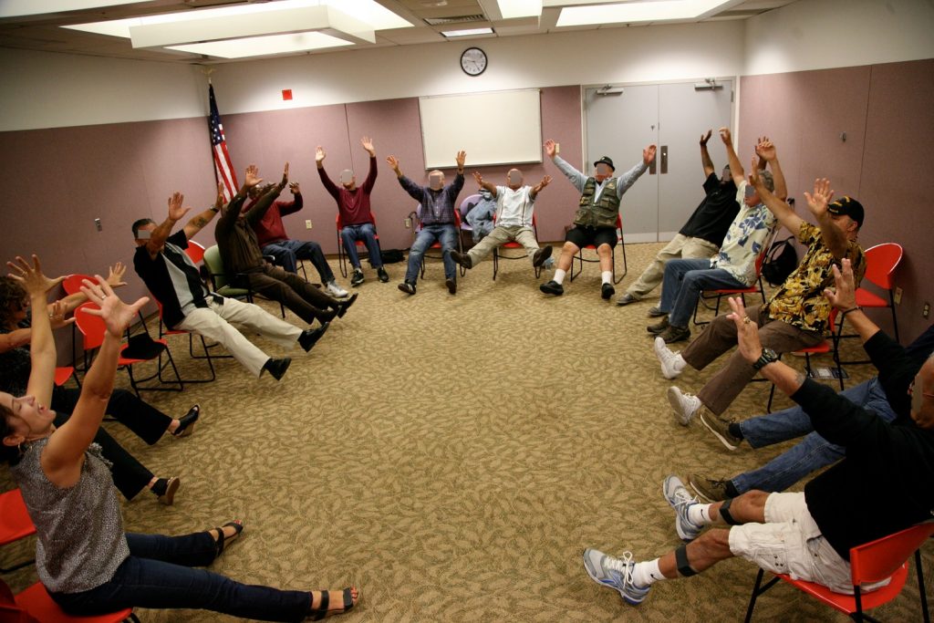 Christine leading group warm-up. Veterans are seated in a circle practicing their "core distal" connectivity. They call it the starfish stretch. Photo by Samuel Primero.