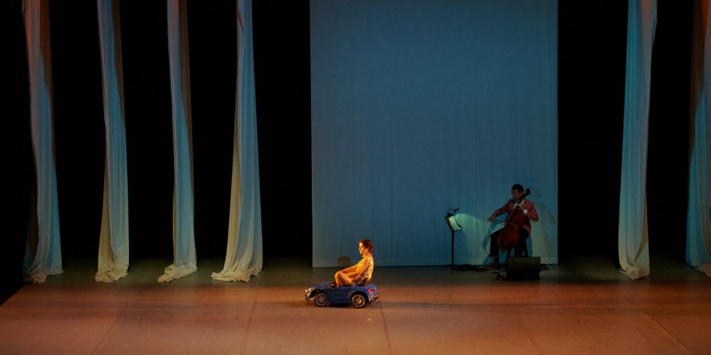 World premiere of "Joy", choreographed by Danielle Agami (L-R) Bronte Mayo (on toy car), Isaiah Gage (on cello) - Photo by Rob LaTour / Shutterstock